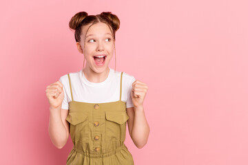Portrait of attractive cheerful pre-teen girl celebrating copy space good news isolated over pink pastel color background