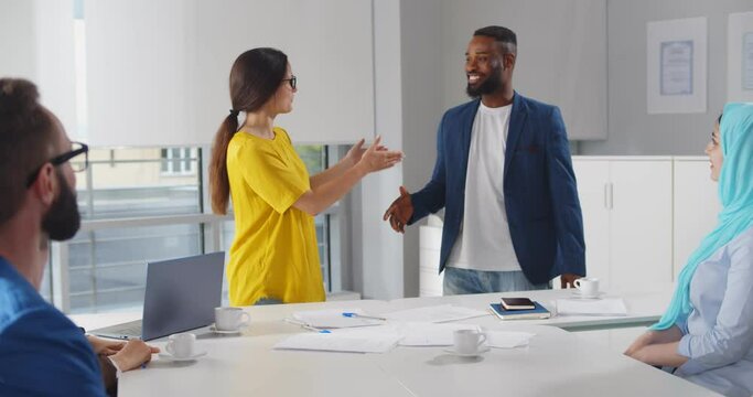 Female leader shaking hands and introducing business coach to employees