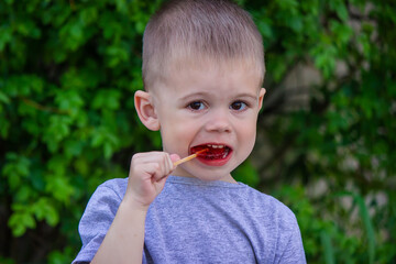 Photo of a boy with a lollipop on a green background. Selective focus