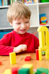 A young builder. Kids playing wooden blocks building tower and sort & stack toys. Kids Play Room. Development and Construction Concept.