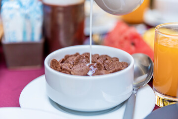 Pouring milk into the bowl with wheat buckwheat bran cereal. Healthy breakfast concept