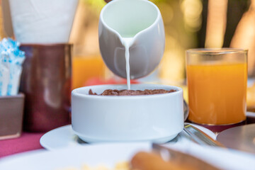 Pouring milk into the bowl with wheat buckwheat bran cereal. Healthy breakfast concept