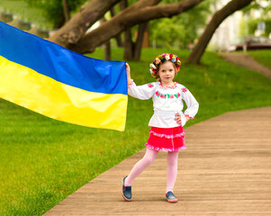 Happy girl with the flag of Ukraine. The girl is dressed in an embroidered shirt - the Ukrainian national dress. August 24 - Independence Day of Ukraine. postcard with patriotic symbols