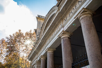 Rome, Italy, partial view of the beautiful façade of a public building with Roman letters. Sun is shining through tree branches with light diffraction effect.