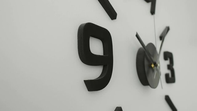 Closer look of the big numbers of the wall clock with the long hand and the short hand