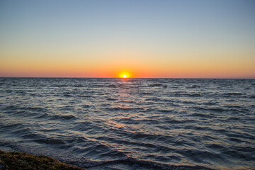 Sea side in sunrise at summer vacation. Colorful sky at sunset on the horizon. Rising Sun Reflecting on Water with Calm Ocean Waves. Hope, spirituality, freedom - concept. Early morning on the beach.