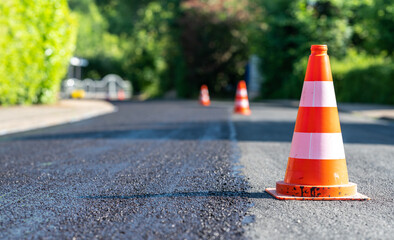 Construction cones marking part of road with a layer of fresh asphalt. - Powered by Adobe