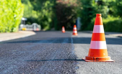 Foto auf Alu-Dibond Construction cones marking part of road with a layer of fresh asphalt. © Fokussiert