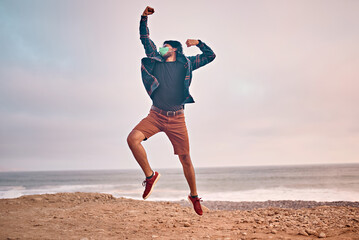 Obraz premium Hombre Joven latino saltando en la arena durante un bello atardecer.. Joven feliz en la playa