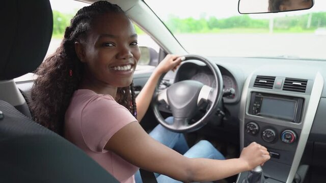 Young black teenage driver seated in her new car