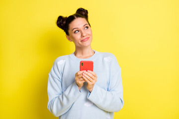 Photo of lady hold smartphone look up empty space think wear blue pullover isolated yellow background