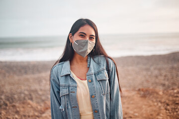 Mujer Joven latina posa caminando en la arena durante un bello atardecer.. Joven feliz  con mascarilla en la playa