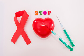 Red ribbon, heart and syringes on white.