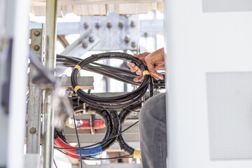 Installing a new mobile network cable behind the phone control cabinet To upgrade to a 5G network, the work of electrical engineers in Thailand