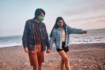 Pareja de jóvenes enamorados caminan por la playa durante un bello atardecer.. Jóvenes felices...