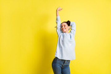 Photo of dreamy inspired lady raise arm close eyes dance wear blue pullover jeans isolated yellow background