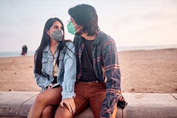 Pareja de jóvenes enamorados sentados en  la playa durante un bello atardecer.. Jóvenes felices...