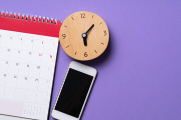 close up of calendar, mobile phone and alaram clock on the purple table background, planning for...