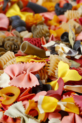 Bright multi-colored pasta of different shapes. Selective focusing on the foreground.