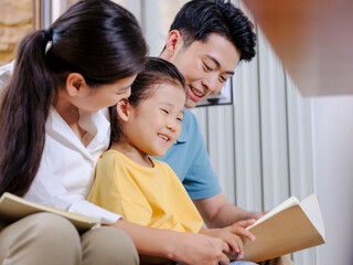 A happy family of three reading on the sofa