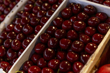 Fresh juicy cherries in containers on the market. Vitamins, healthy eating and veganism. Close-up....