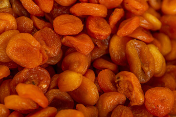 There are a lot of dried apricots on the counter in the market. Healthy food, vitamins and veganism. Close-up. Top view.