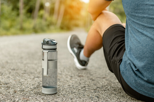 Close up water bottle. Tired sport man is resting after exercise with bottle of water.