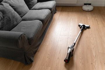Cleaning wooden floor with wireless vacuum cleaner. Handheld cordless cleaner. Household appliance. Housework modern equipment - obrazy, fototapety, plakaty