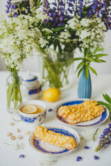 Lemon eclairs and lemon tea, in a vintage tea set, and flowers, over white background.