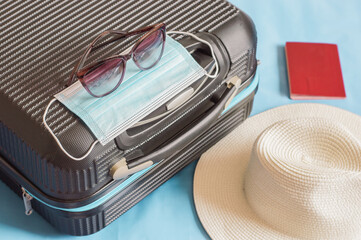 Flat lay composition with suitcase, protective mask,hat,glasses,passport, space for text. Travel concept