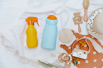 Two bottles of sunscreen, baby beach essentials and swimsuit. Sunscreen protect for kids. Top view,...