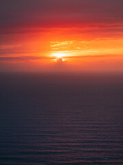 Sun setting behind the clouds on the Atlantic Ocean with very calm sea