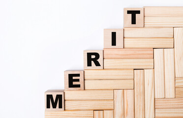 On a light background, wooden blocks and cubes with the text MERIT