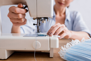 Cropped view of seamstress sewing medical mask on machine