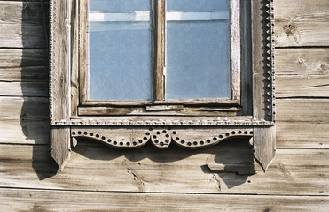 Part of the window with elements of decorations of an old Russian wooden house.