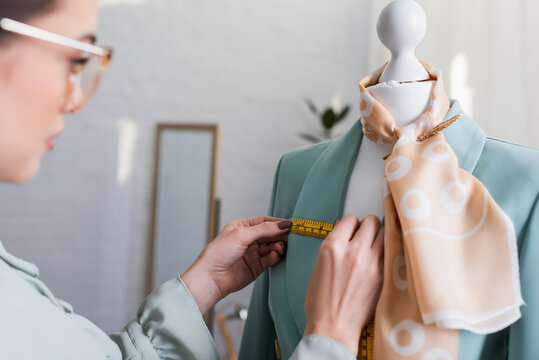 Blurred seamstress measuring jacket on mannequin