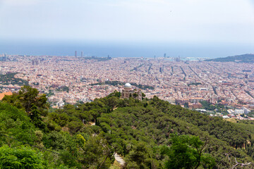 View over Barcelona city from Tibidabo mountain in Spain during summer sunny day, trees, buildings and sea on one shoot.