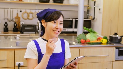 バインダーをもってご飯の献立に悩む家事代行の女性作業員