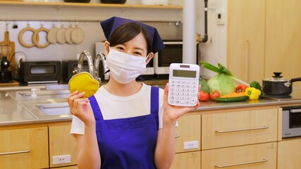 電卓を持ちやりくりに悩むマスクをした家事代行の女性作業員