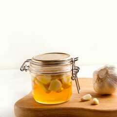 Honey with garlic on a white plate next to the ingredients. Copy space