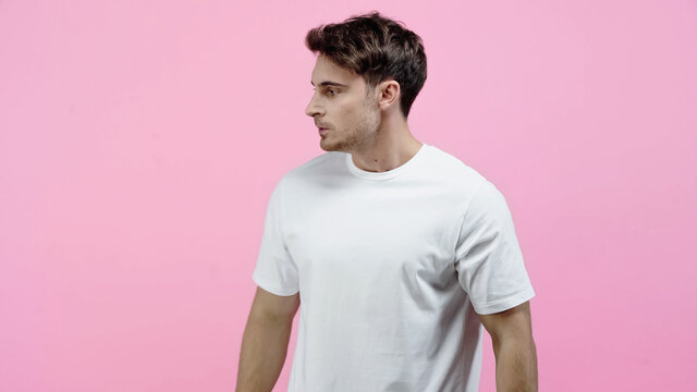 Side view of angry man in white t-shirt looking away isolated on pink