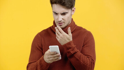 Offended man using mobile phone isolated on yellow