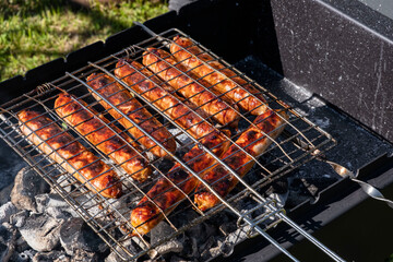 Grilled sausages on the charcoal grill, summer picnic in nature, barbecue bbq grill traditional German bratwurst hot dogs 