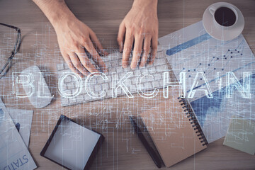 Double exposure of man's hands typing over computer keyboard and crypto currency theme hologram...