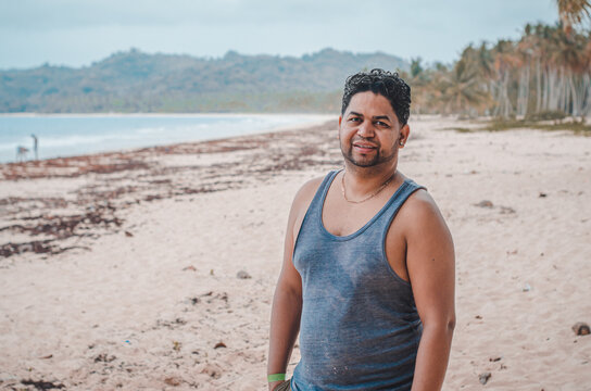 Latin man with dark skin on the beach looking at the landscape in flannel