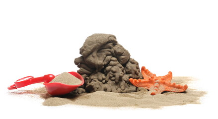 Plastic beach toys and starfish in wet sand pile isolated on white background