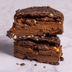 Alfajor artesanal de chocolate y mani sobre una mesada de marmol.