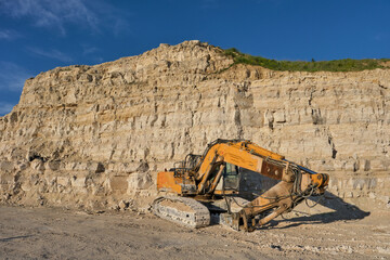 Obraz premium Excavator stands on the background of a stone quarry.
