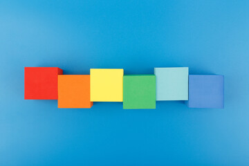 Flat lay with LGBT rainbow symbol made of colorful cubes on blue background. Concept of Pride...