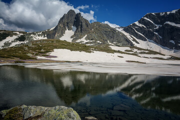 Obraz premium Beautiful spring mountain landscape, Rila Mountain, Seven Rila Lakes, Bulgaria. Frozen glacial lakes against the backdrop of a high rocky peak, meadows with blooming crocuses in the foreground.